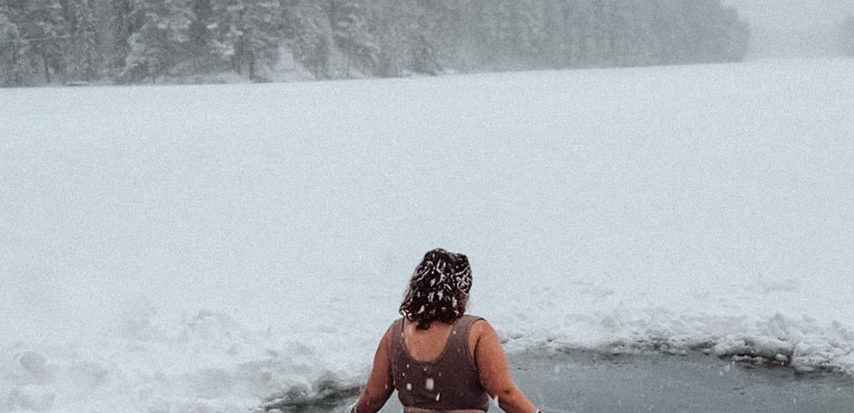 person bader i et hull i isen på vinteren