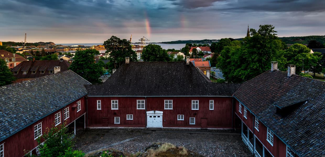en trebygning med regnbue og hav i horisonten