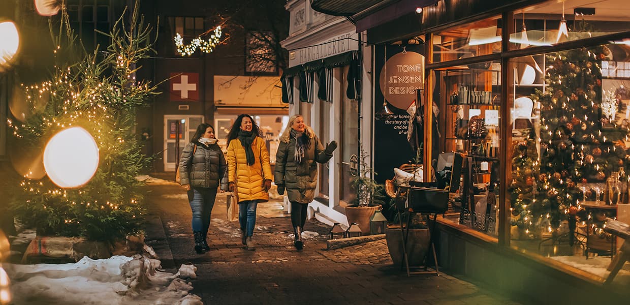 tre mennesker i vinterklær går i en julepyntet gate