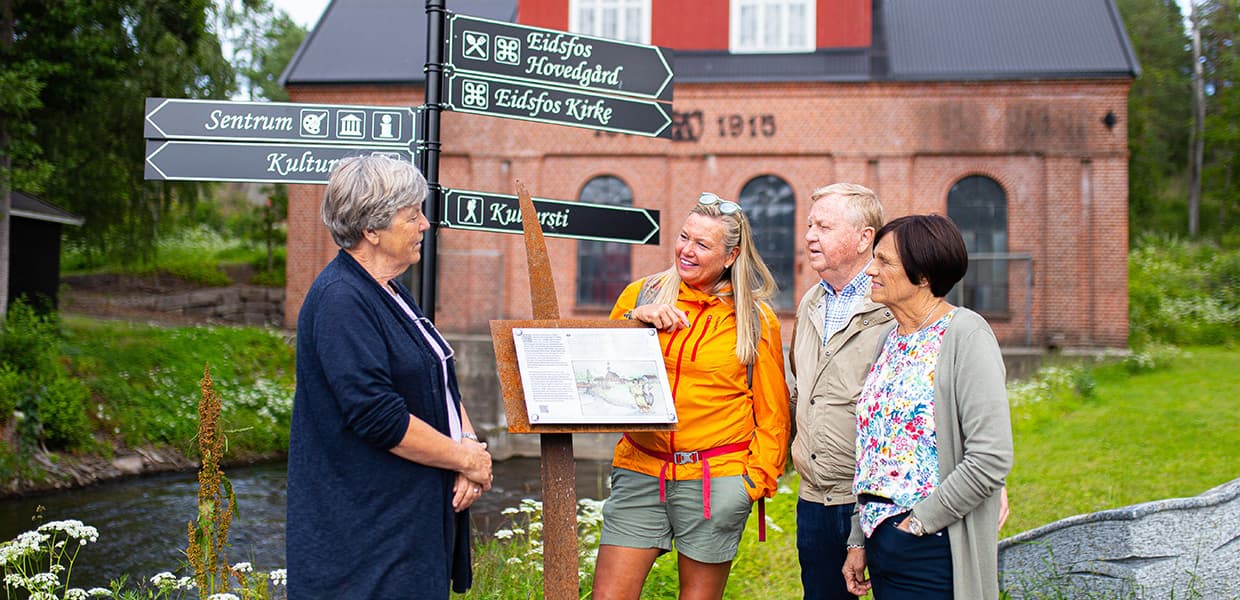 fire mennesker står foran et gammelt bygg og skilt