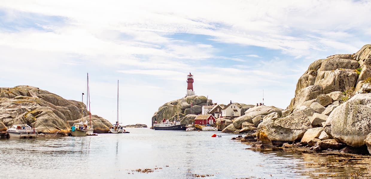 Utsikt mot Svenner fyr med seilbåt og båter på vannet