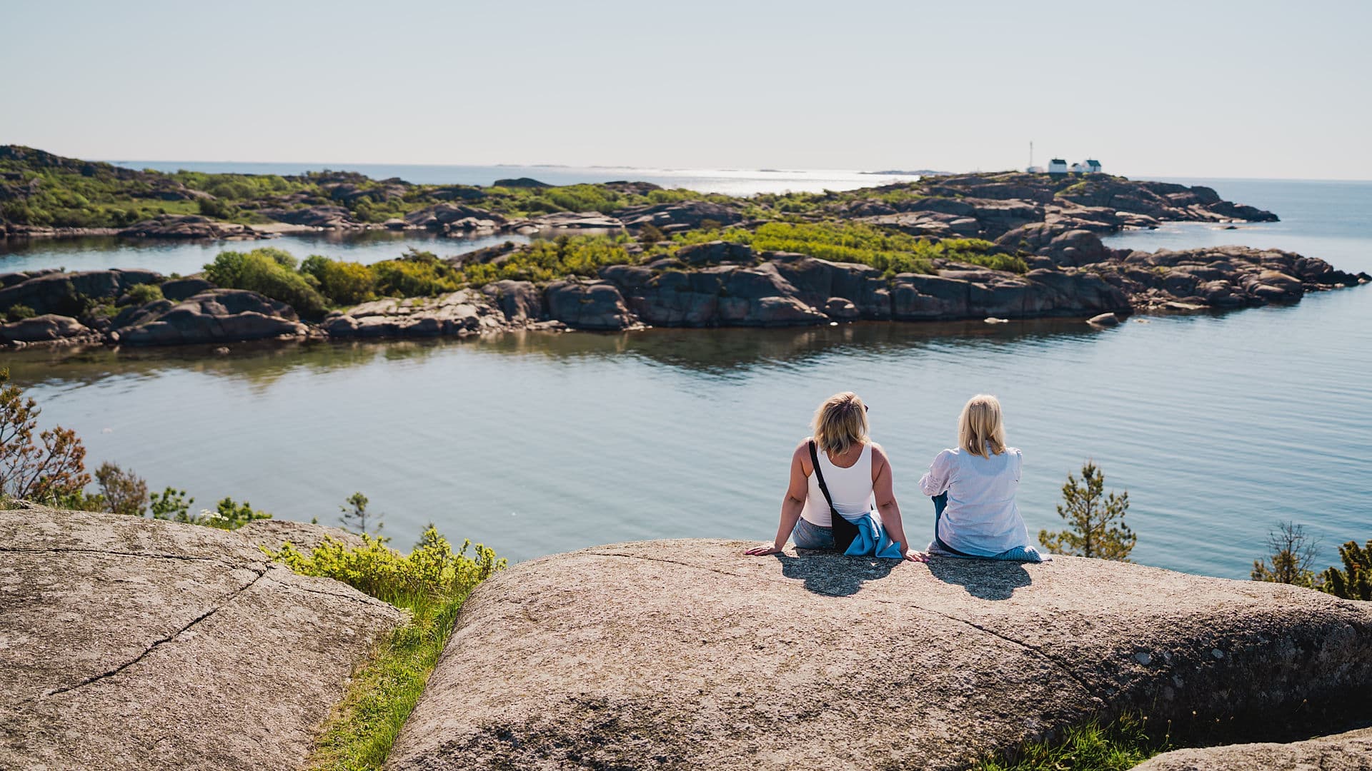 To personer sitter på svaberg med utsikt over skjærgården ved Stavern i Vestfold.
